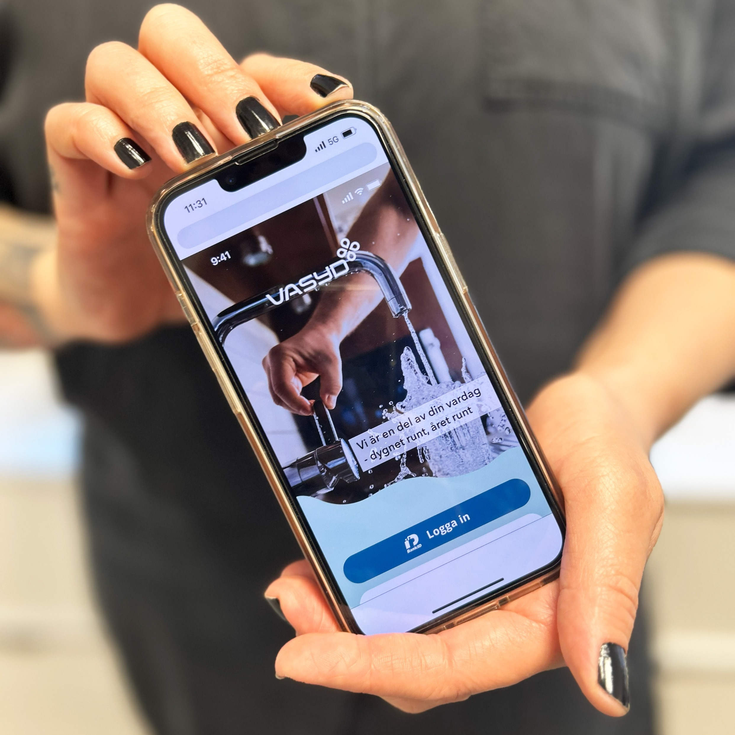 Image of a person holding a mobile phone with VA SYDs app